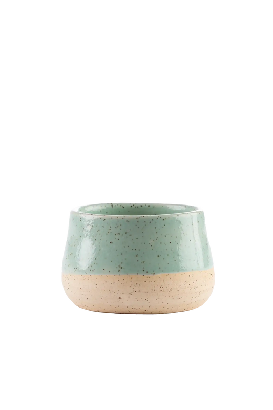 Vela aromática artesanal em recipiente de cerâmica artesanal com cera vegetal de coco na cor verde-mangaba com fragrância fresca de notas de limão siciliano, rosa, jasmim e vetiver, proporciona uma queima limpa e duradoura, exalando uma fragrância leve que renova as energias do lar.