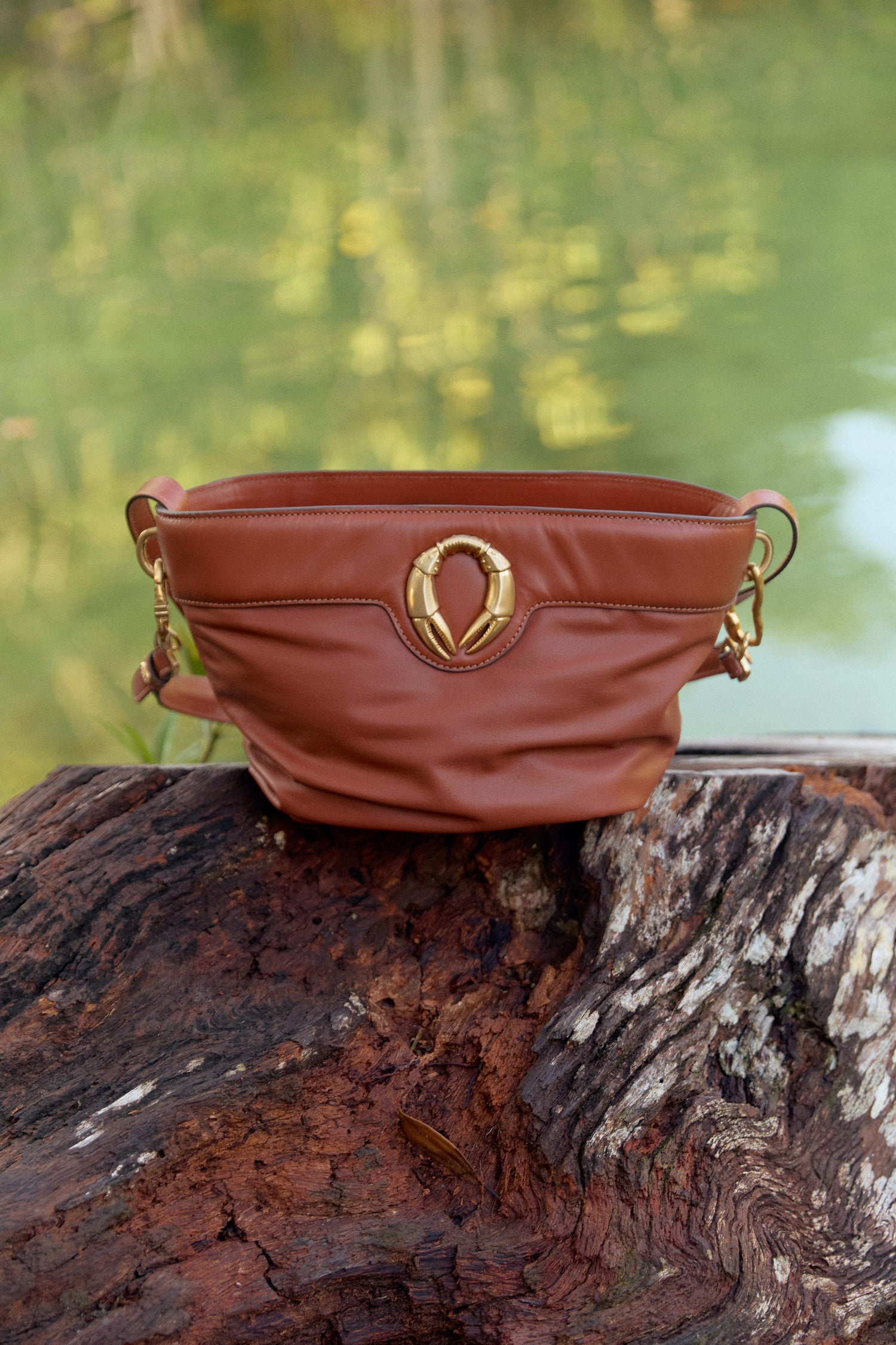 Bolsa marrom com detalhe dourado em tronco de árvore, design brasileiro e sofisticado