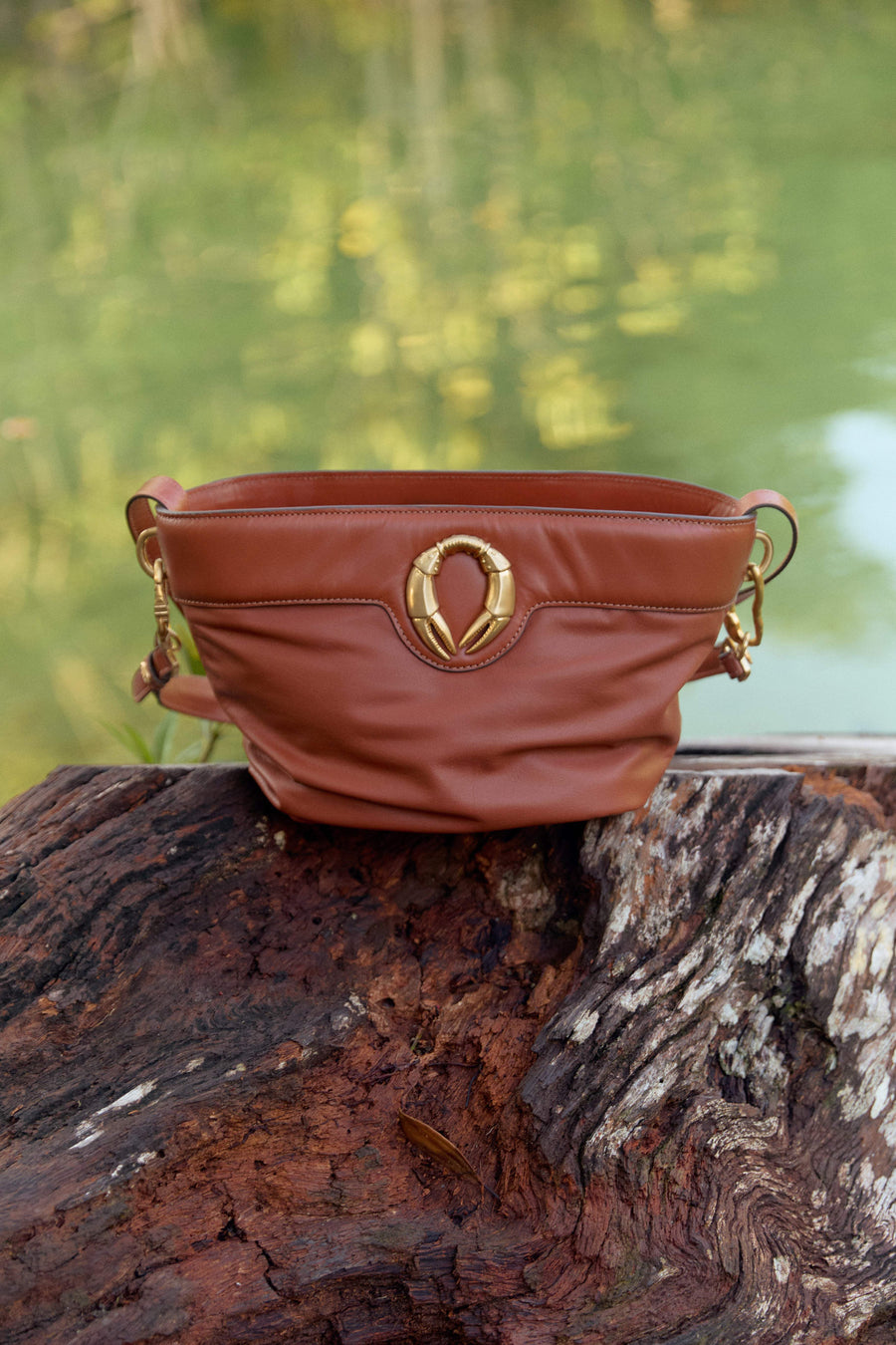 Bolsa marrom com detalhe dourado em tronco de árvore, design brasileiro e sofisticado