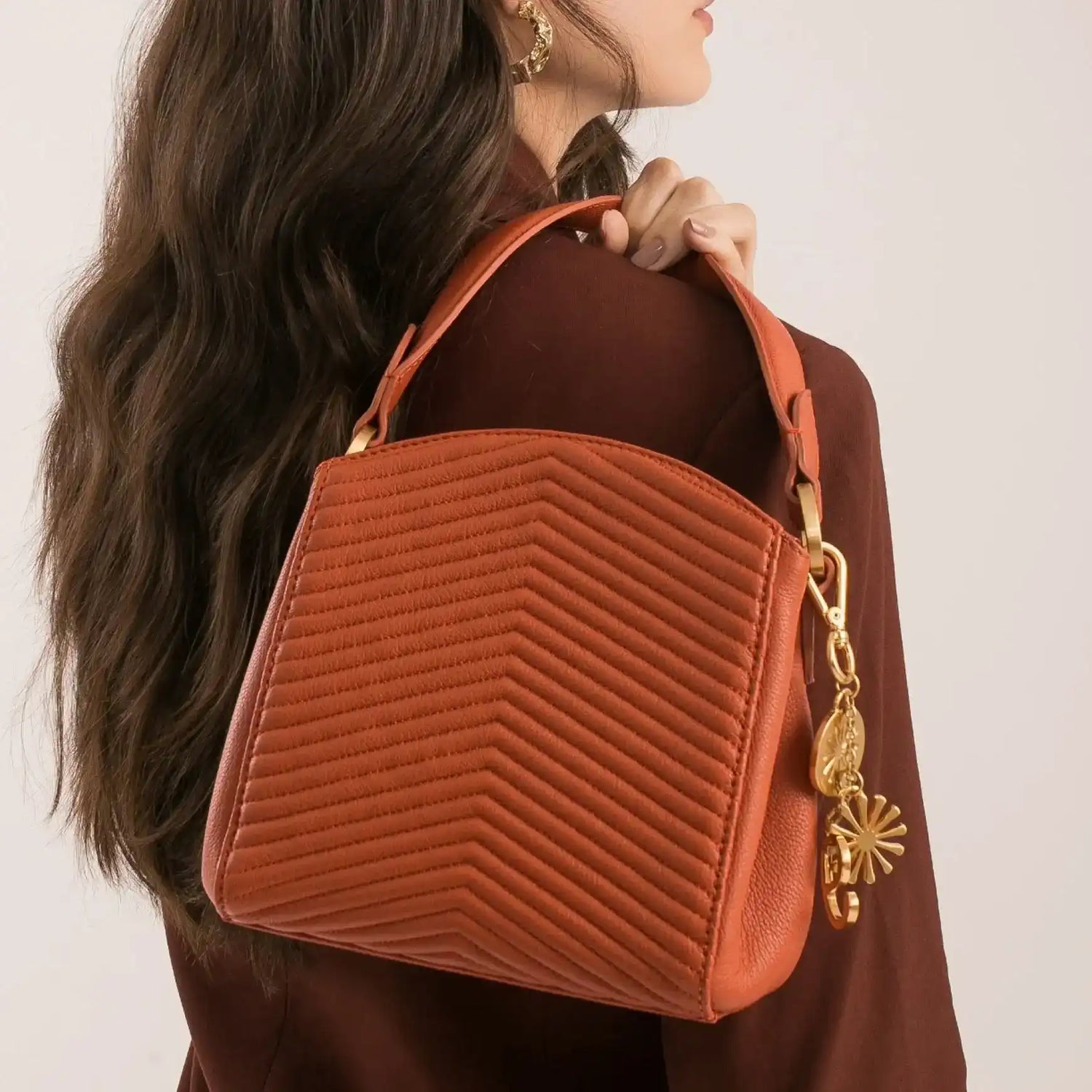 Bolsa marrom com costura em zig-zag e detalhes dourados, estilo sofisticado e funcional