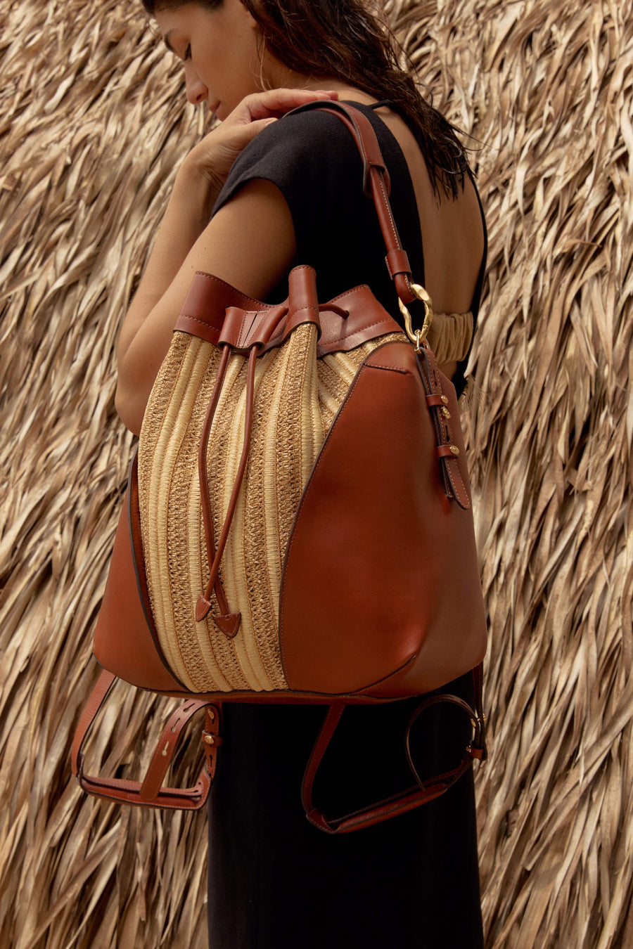 Bolsa bucket bag em couro marrom e palha, com alça de ombro e detalhes dourados, ideal para looks sofisticados e funcionais.