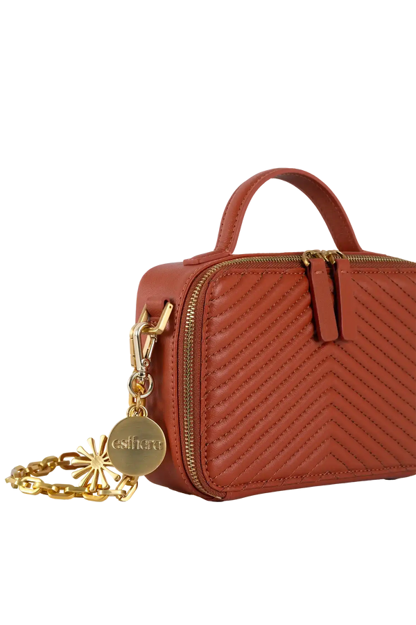 Bolsa marrom com costura em zigue-zague, alça de corrente dourada e detalhe da marca Esthera