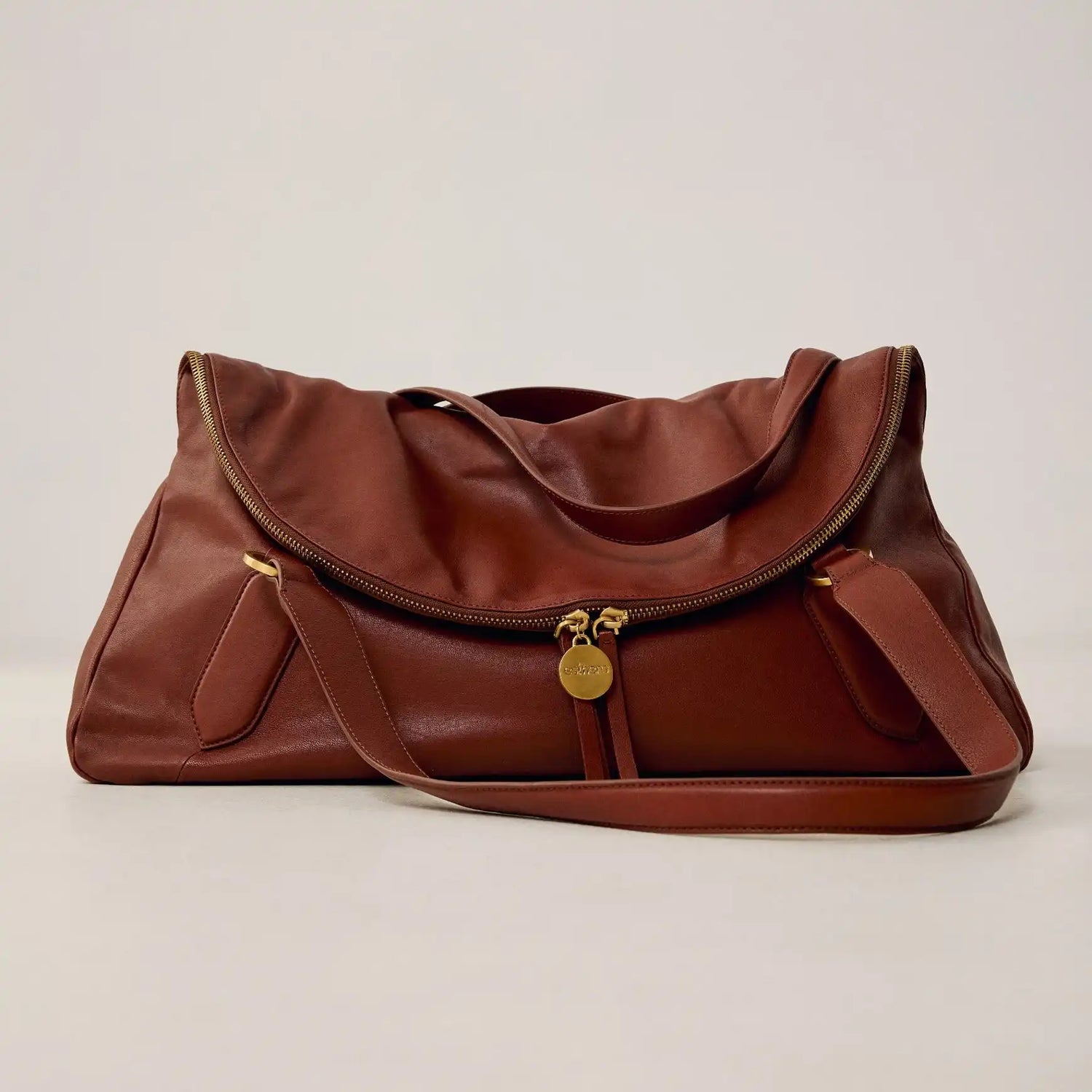 Bolsa marrom em couro com design brasileiro, alça longa e detalhes dourados, sofisticada e funcional.