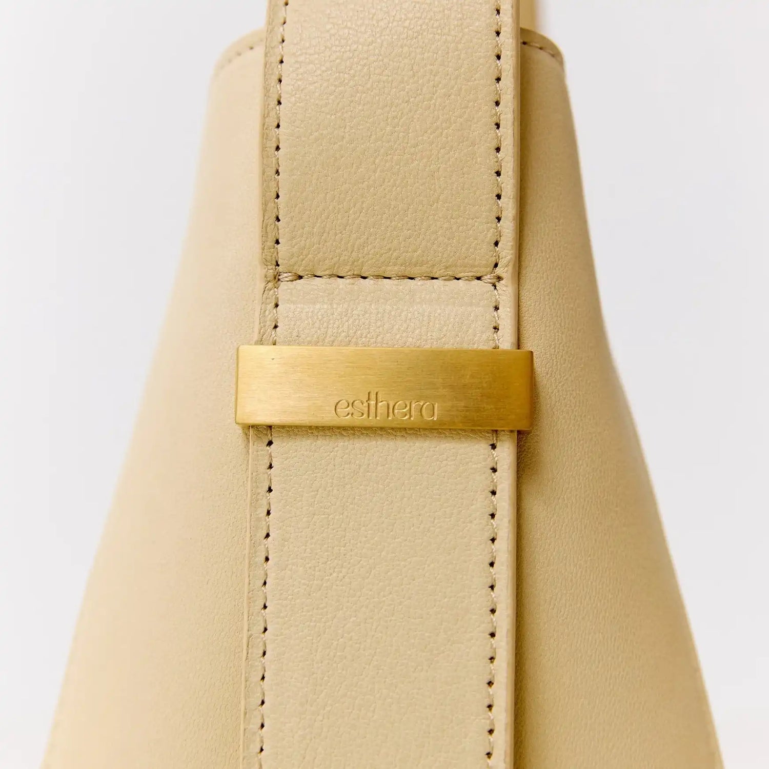 Bolsa bege com detalhe em metal dourado e logo esthera, design sofisticado e acabamento premium
