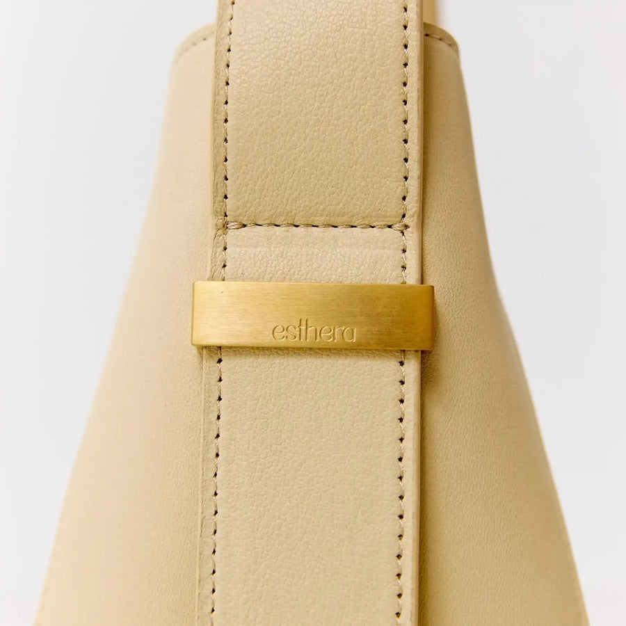Bolsa bege com detalhe em metal dourado e logo esthera, design sofisticado e acabamento premium