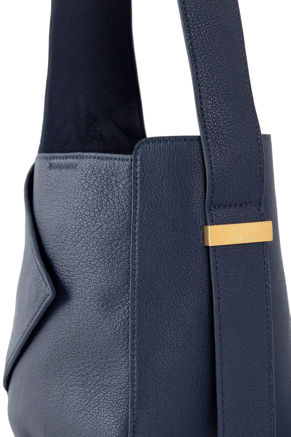 Bolsa de couro azul marinho com detalhe dourado e textura sofisticada, ideal para uso diário.