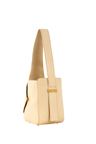 Bolsa bege com alça longa e detalhe dourado, design minimalista e sofisticado para uso diário.