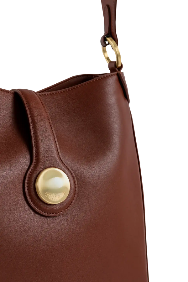 Bolsa marrom com detalhe dourado e logo 'esthera' visível