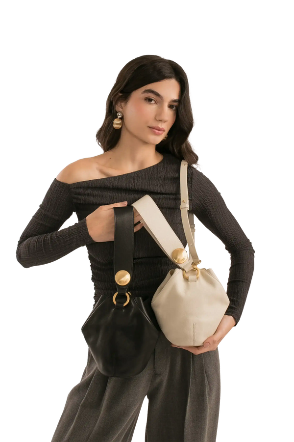 Bolsa bucket preta e bege com alça larga e detalhes dourados, estilo sofisticado e funcional