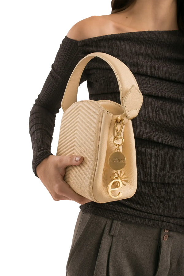 Bolsa bege com textura em zig-zag e detalhes dourados, ideal para looks sofisticados e funcionais.