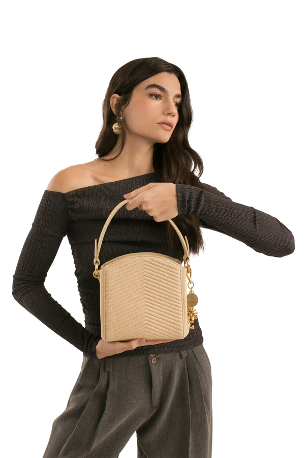 Bolsa bege com textura em V, alça de mão e detalhes dourados, combinando com look elegante