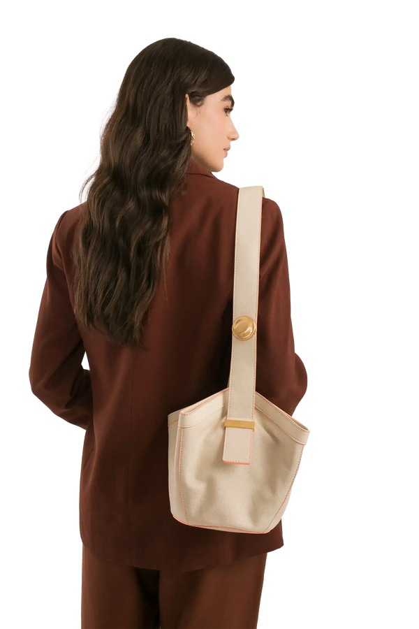 Bolsa bege com detalhes em rosa, usada por mulher de blazer marrom, estilo sofisticado e funcional.