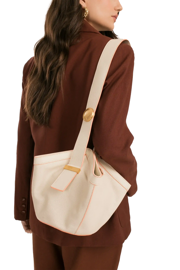Bolsa branca com detalhes em rosa, alça larga e fecho dourado, combinando com blazer marrom.