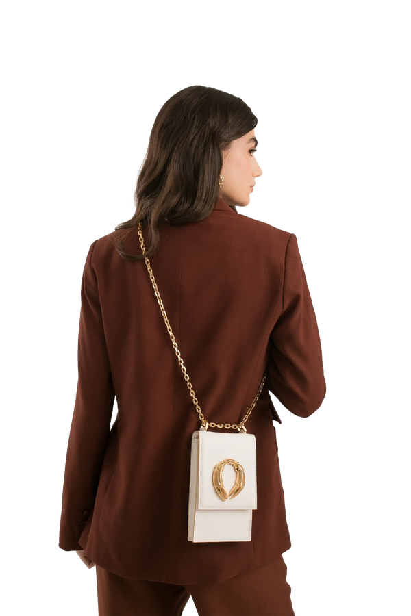 Bolsa branca com corrente dourada e detalhe em forma de coração, combinando com blazer marrom