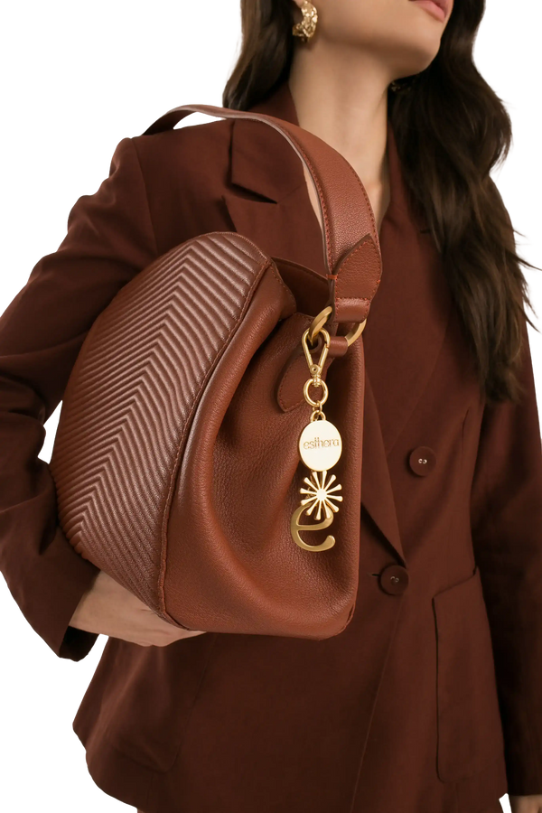Bolsa marrom com textura em zig-zag e detalhe dourado, combinando com blazer elegante