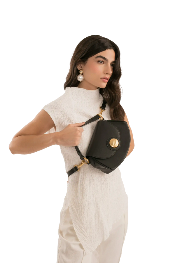 Bolsa preta com detalhe dourado e alça ajustável, combinando com look branco elegante
