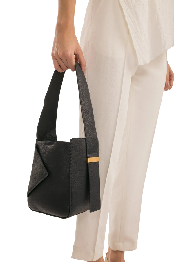 Bolsa preta elegante com alça longa e detalhe dourado, combinando com look sofisticado