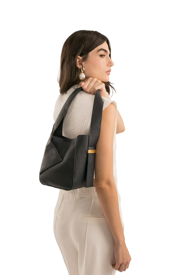 Bolsa preta elegante com alça larga e detalhe dourado, combinando com look sofisticado