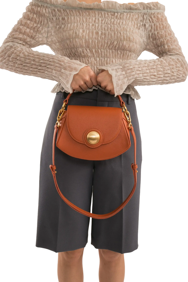 Bolsa marrom com detalhe dourado, combinando com look sofisticado e moderno