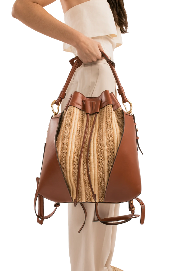 Bolsa bucket de couro marrom com detalhe em palha trançada, alça de mão e design sofisticado.