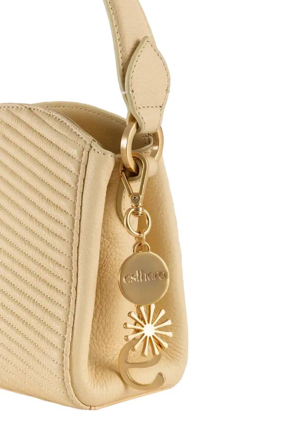 Bolsa bege com detalhe em dourado e charme estilizado da Esthera, design brasileiro e sofisticado