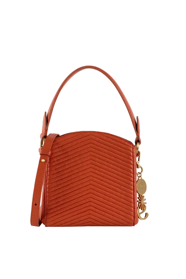 Bolsa laranja com costura em zig-zag, alça de mão e detalhe dourado, design brasileiro sofisticado e funcional