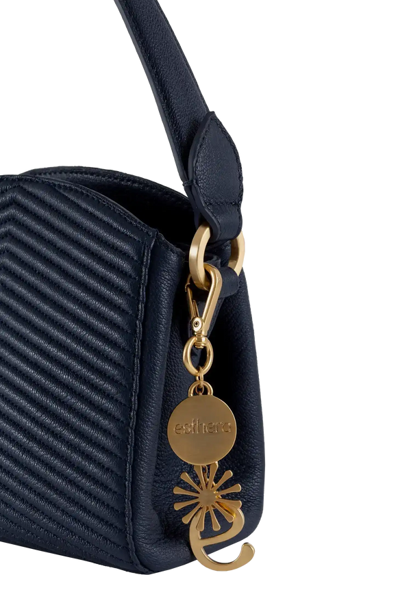 Bolsa preta com textura em relevo e detalhe dourado da Esthera, design brasileiro sofisticado