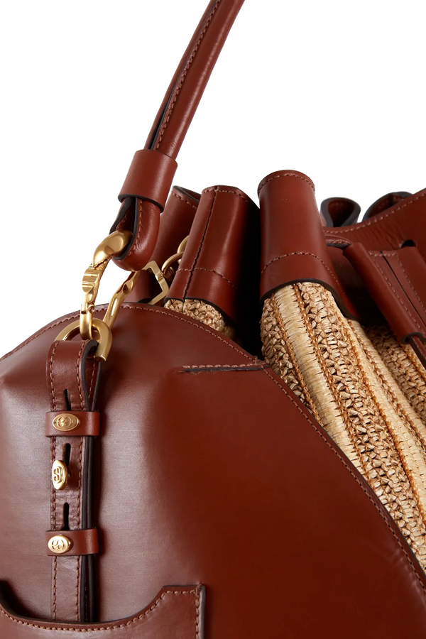 Bolsa de couro marrom com detalhes em palha e metais dourados, design sofisticado e funcional.