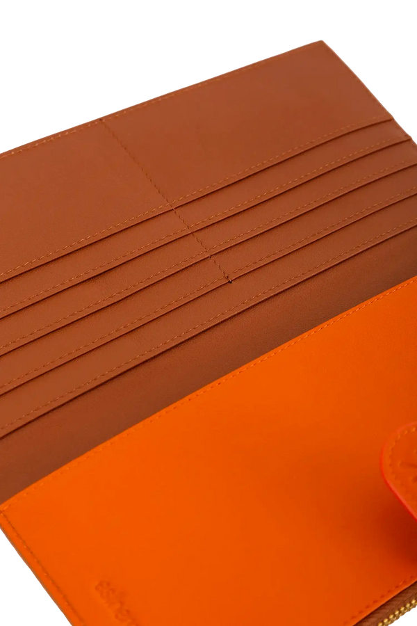 Porta-passaporte em couro legítimo nas cores laranja e marrom com divisórias exatas para passaporte, documentos de viagem e cartões de embarque, formato ergonômico e slim que cabe no bolso ou na bolsa sem criar volumes desnecessários.